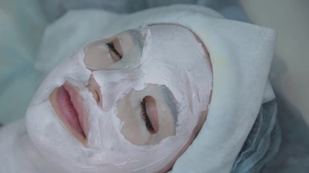 Bella donna si trova con una maschera sul viso in un salone di bellezza . — Video Stock