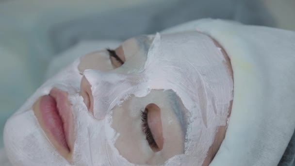 Beautiful woman lies with a mask on her face in a beauty salon. — Stock Video