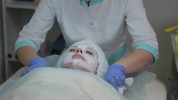 Professionele cosmetoloog vrouw verwijdert masker van klanten gezicht met natte doekjes. — Stockvideo