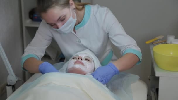 Profesyonel kozmetikçi kadın ıslak mendille müşterilerin yüzündeki maskeyi çıkarıyor.. — Stok video
