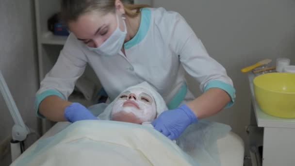 A mulher cosmetologist profissional remove a máscara da cara de clientes com toalhetes molhados . — Vídeo de Stock