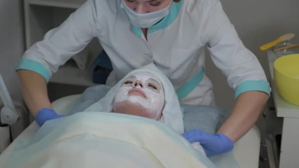 Professional cosmetologist woman removes mask from clients face with wet wipes. — Stock Video