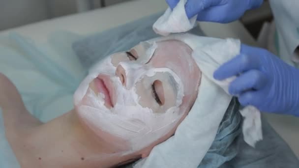 La donna cosmetologa professionista toglie la maschera da faccia di clienti con salviettine umide . — Video Stock