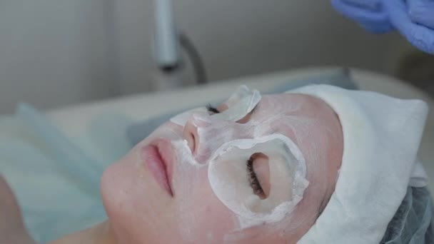 Professional cosmetologist woman removes mask from clients face with wet wipes. — Stock Video