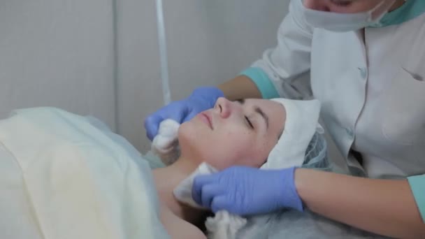 La donna cosmetologa professionista toglie la maschera da faccia di clienti con salviettine umide . — Video Stock