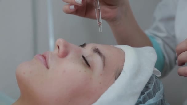 Mujer esteticista profesional aplicando aceite a la piel en una cuña con una pipeta . — Vídeo de stock