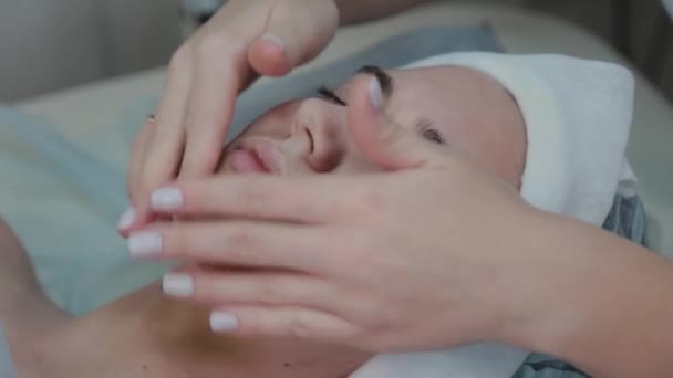 Mulher esteticista profissional realiza massagem facial para mulher cliente . — Vídeo de Stock