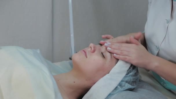 Wanita ahli kecantikan profesional melakukan pijat wajah untuk wanita klien . — Stok Video