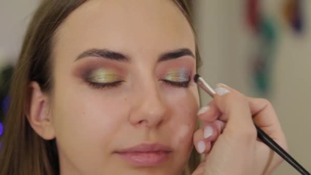 Artista de maquillaje profesional pone sombra de ojos en un cliente de un salón de belleza . — Vídeos de Stock