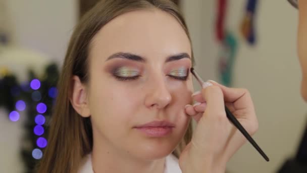 Artista de maquillaje profesional pone sombra de ojos en un cliente de un salón de belleza . — Vídeos de Stock