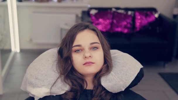 Ung flicka i en skönhetssalong i en stol. — Stockvideo
