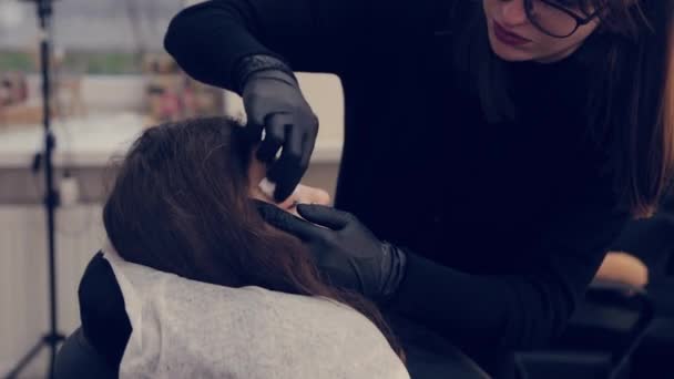 Профессиональная женщина мастер брови чистит брови клиенту в салоне красоты . — стоковое видео