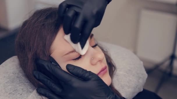 El amo profesional de las cejas de la mujer limpia las cejas al cliente en salón de belleza . — Vídeo de stock