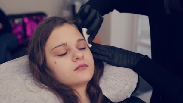 Femme professionnelle maître des sourcils nettoie les sourcils au client dans le salon de beauté . — Video