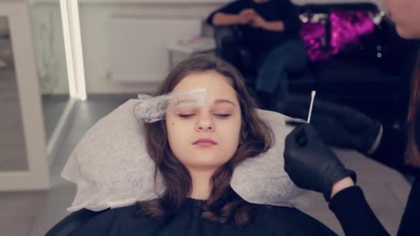 Professionnel maître sourcil femme enlève le film du sourcil et enlève le liquide sur les sourcils dans un salon de beauté . — Video