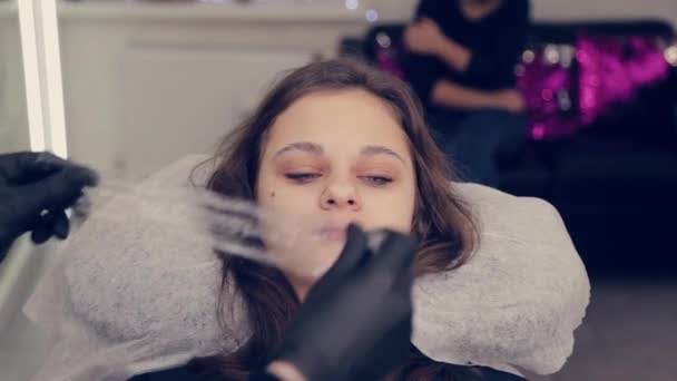 Femme professionnelle maître des sourcils met le film sur les sourcils dans un salon de beauté . — Video
