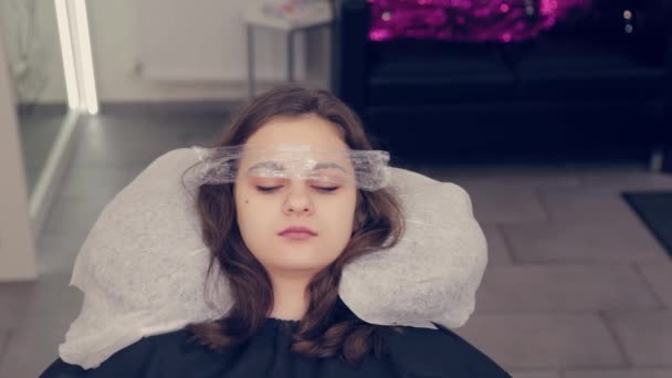 Menina bonita com um filme em sobrancelhas em um salão de beleza . — Vídeo de Stock