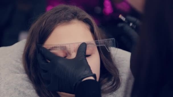 O mestre profissional da sobrancelha da mulher faz a marcação nas sobrancelhas ao cliente no salão de beleza . — Vídeo de Stock