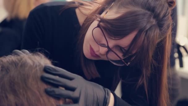 Profesional maestro de cejas mujer arrancando las cejas con pinzas al cliente en el salón de belleza . — Vídeo de stock