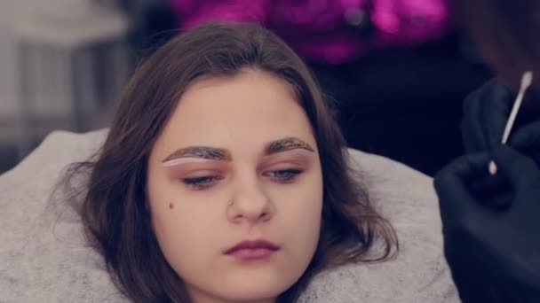 Professionelle Frau Augenbrauen Master Griffe ein Wattestäbchen mit Augenbrauen Client im Schönheitssalon. — Stockvideo
