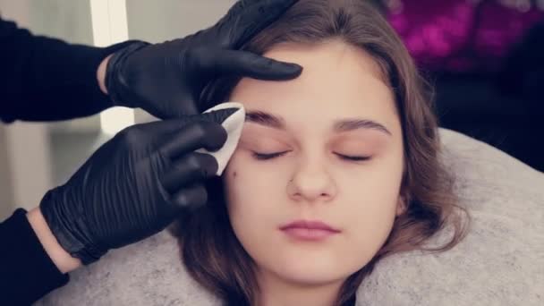 Professionell kvinna ögonbrynsmästare rengör ögonbryn till kund i skönhetssalong. — Stockvideo