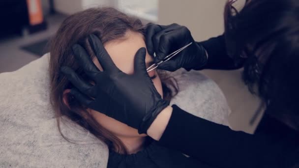 Profesional maestro de cejas mujer arrancando las cejas con pinzas al cliente en el salón de belleza . — Vídeo de stock