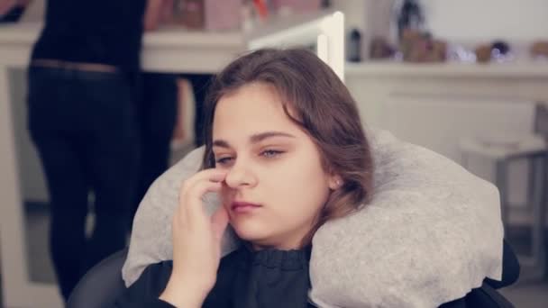 Fiatal lány egy szépségszalonban egy székben. — Stock videók