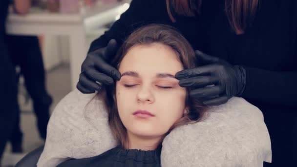 Maestro profesional de la ceja de la mujer que hace el masaje de la ceja al cliente en salón de belleza . — Vídeo de stock