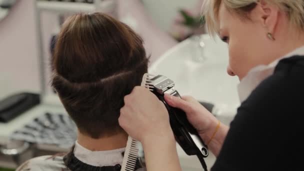 Επαγγελματική κομμώτρια γυναίκα κοπής μαλλιών στην πελάτισσα με ψαλιδιστή μαλλιών. — Αρχείο Βίντεο