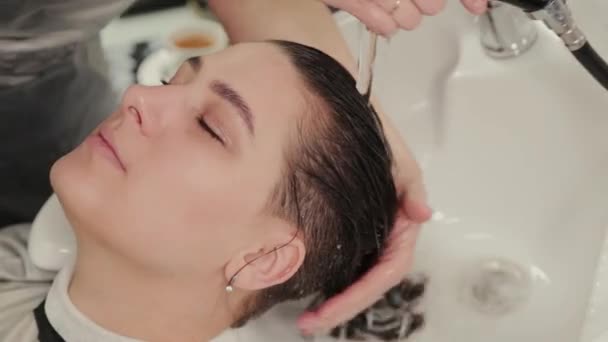 Peluquería profesional mujer lava el cabello al cliente . — Vídeo de stock