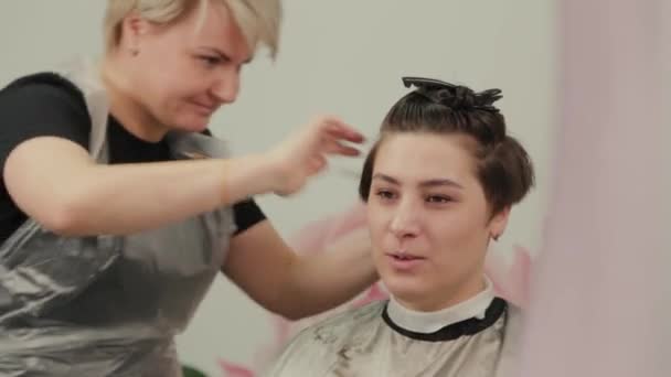 Peluquería profesional mujer haciendo peinado en el pelo mojado al cliente . — Vídeos de Stock