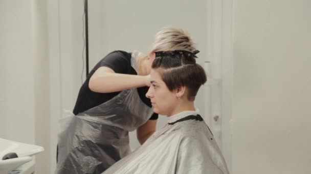 Peluquería profesional mujer haciendo peinado en el pelo mojado al cliente . — Vídeos de Stock