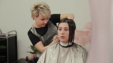 Profesyonel kuaför kadın müşteriye ıslak saç stili yapıyor..