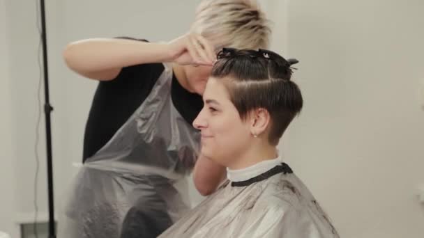 Peluquería profesional mujer haciendo peinado en el pelo mojado al cliente . — Vídeos de Stock