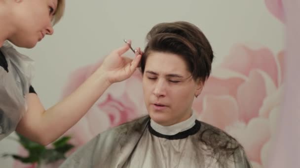 Coiffeur professionnel femme faisant coiffure sur cheveux mouillés au client . — Video