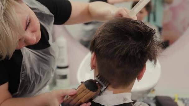 Professional hairdresser woman haircuts a girl with a hairdresser. — 비디오