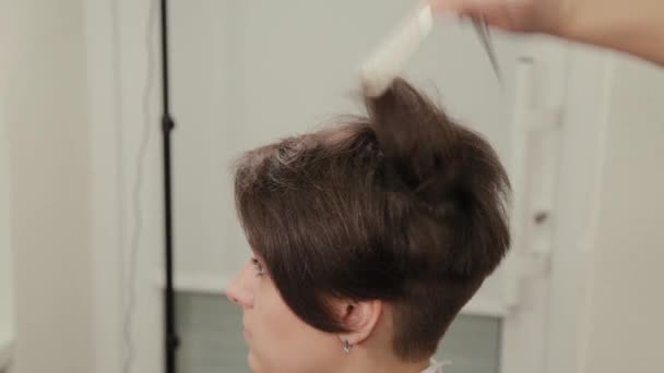 Professionelle Friseurin Frau frisiert ein Mädchen mit einem Friseur. — Stockvideo