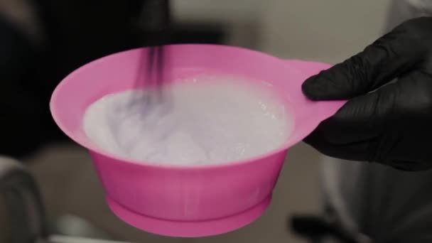 Professional hairdresser woman stirs hair balm in a special container. — Stock Video