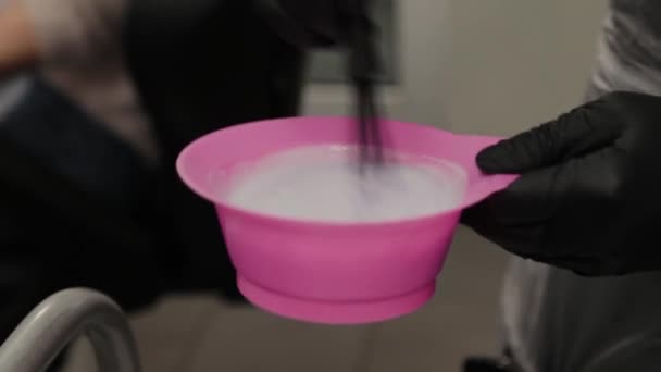 Professional hairdresser woman stirs hair balm in a special container. — Stock Video