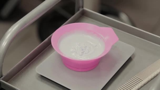 Professional hairdresser woman stirs hair balm in a special container. — Stock Video