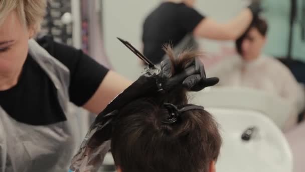 Parrucchiere professionista donna tinge i capelli delle ragazze con tintura per capelli su lamina . — Video Stock