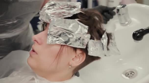Professionele kapper vrouw wast haar kleurstof meisje. — Stockvideo