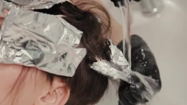 Professional hairdresser woman washes hair dye girl. — Stock Video