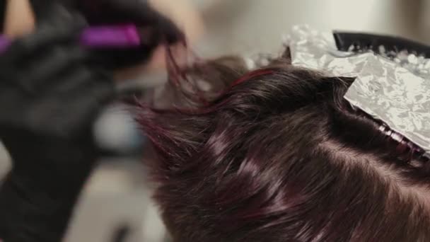 プロの美容師の女性は髪染めの女の子を洗う. — ストック動画