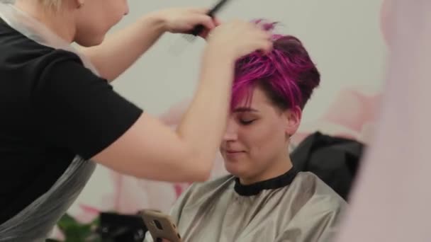 Professional hairdresser woman styling girl after dyeing hair. — Stock Video
