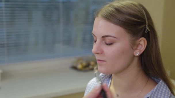 Professionell make-up artist applicerar foundation på ansikte till kund. — Stockvideo