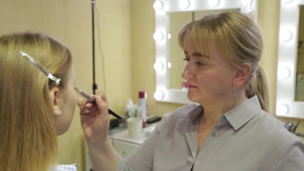 Professionell make-up artist applicerar foundation på ansikte till kund. — Stockvideo