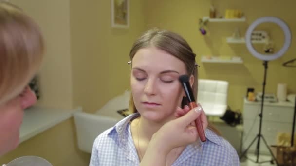 Professionele make-up kunstenaar het aanbrengen van make-up borstel aan de klant. — Stockvideo