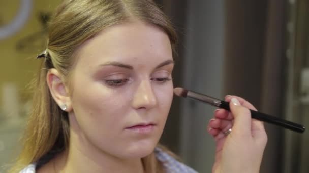 Profesyonel makyaj sanatçısı müşteriye makyaj fırçası uyguluyor. — Stok video