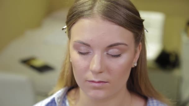 Artista de maquillaje profesional con un cepillo aplica sombra de ojos a un cliente en un salón de belleza . — Vídeos de Stock